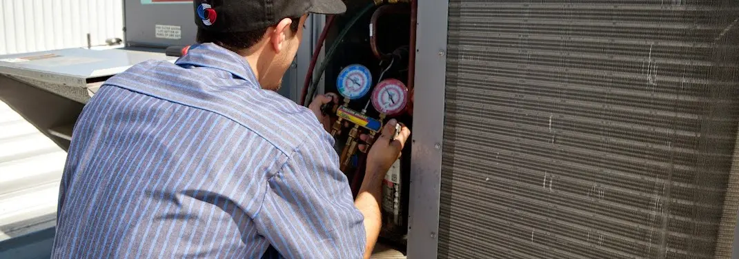 HVAC technician servicing a condenser unit in Eastpointe
